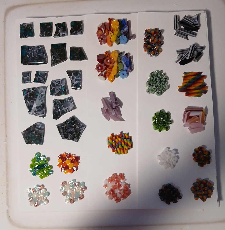 kiln shelf with a bunch of glass teak pieces and a bunch of little clusters of murrine