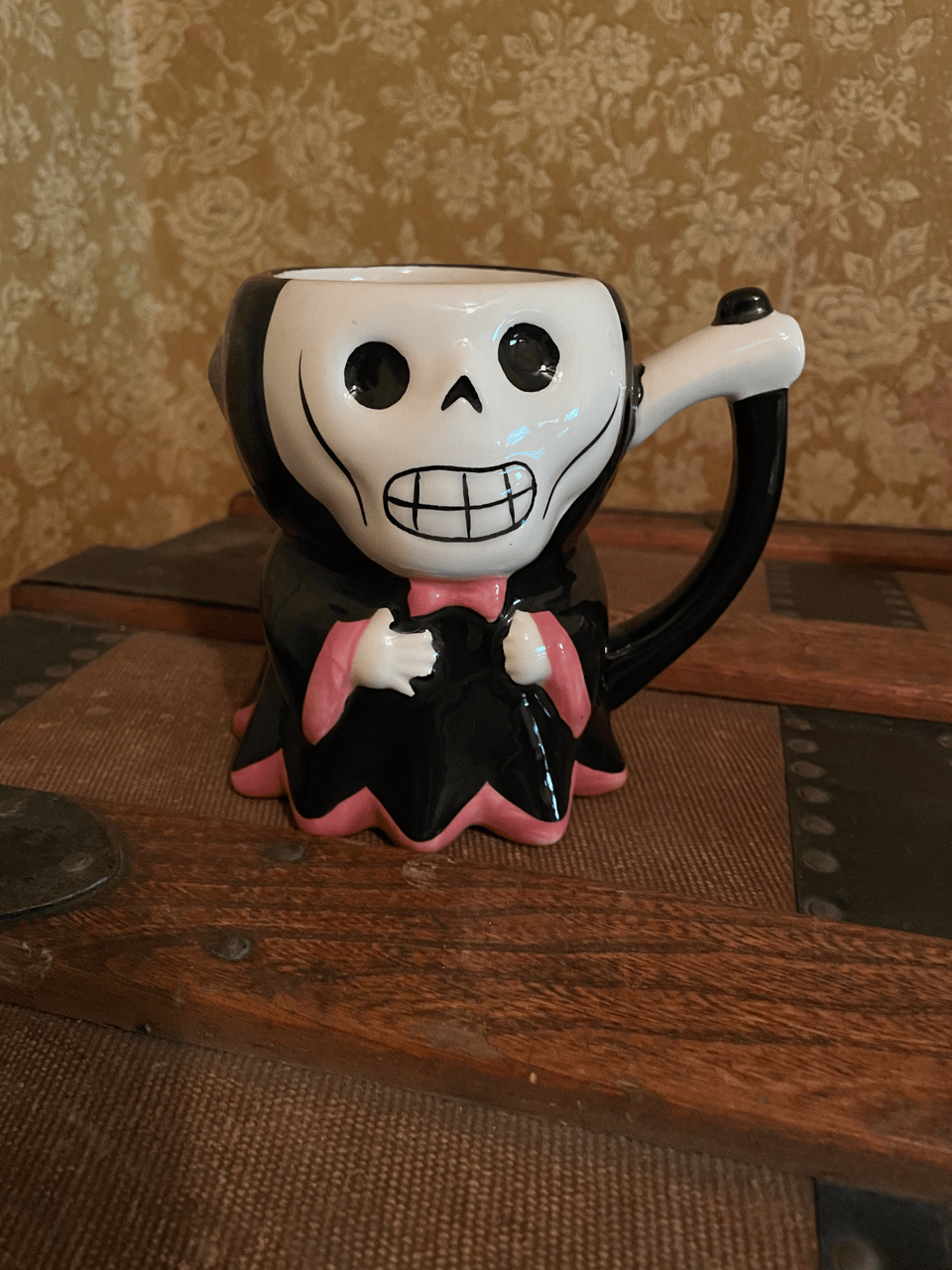 A cute version of death with a bow-tie and a scythe and an open head to drink out of