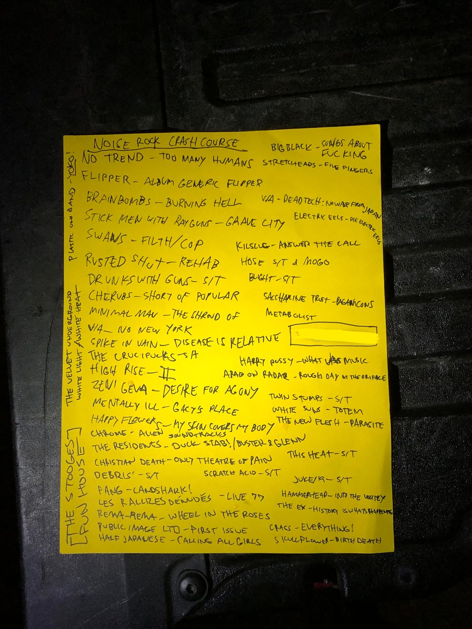 A yellow piece of paper with a list of artist names and album titles of the noise rock mileau, transcribed elsewhere on this page.