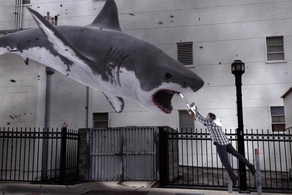 A shark dangles midair, in a city environment. From the "Sharknado" francise.