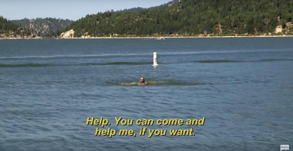 A white man's head is poking above a body of lake water. He's yelling, "Help. You can come and help me, if you want." It's a very memorable scene from the Bravo reality tv show, Vanderpump Rules.
