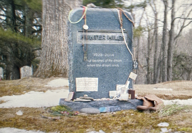 the fictional grave of a music star covered with gifts from fans