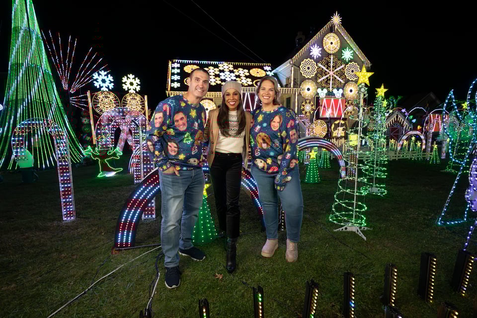 three people posing in front of a christmas light display