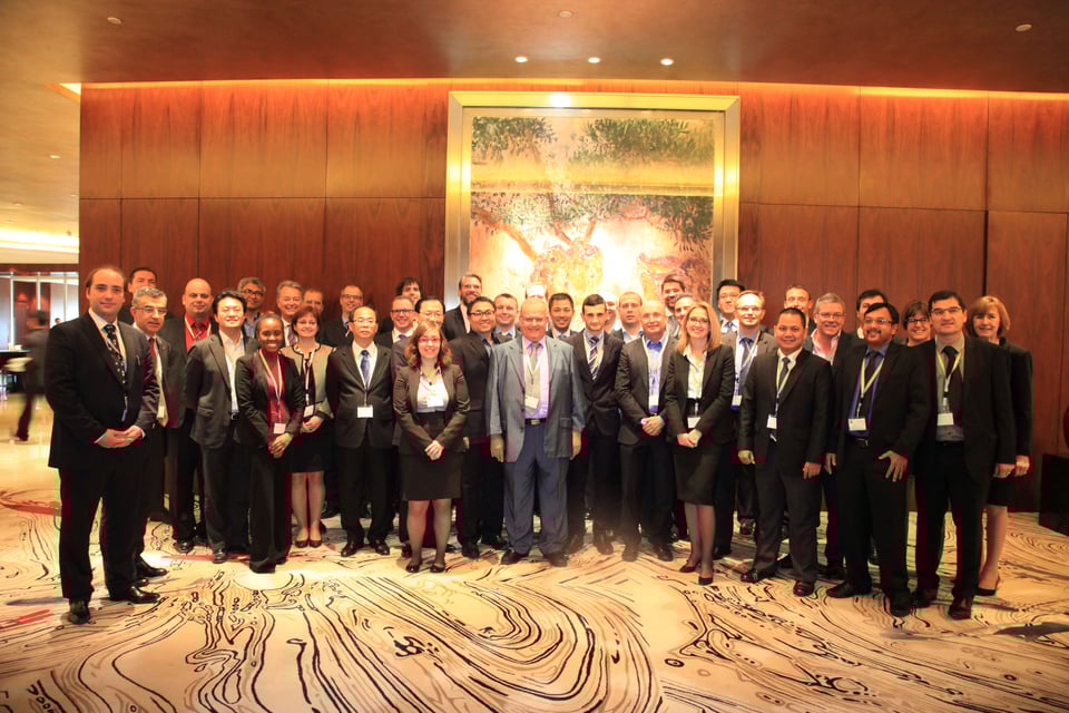 Large group of business people - mostly men, in suits - lined up for a photo in a hotel or conference venue, in Shanghai.