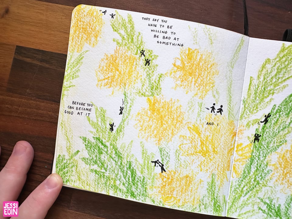 A close up look at the first page of the Be Willing to Be Bad At It comic. The texture of the paper and the colored pencils is really prominent, and the tiny figures stand out strongly against the light yellow and green colors.