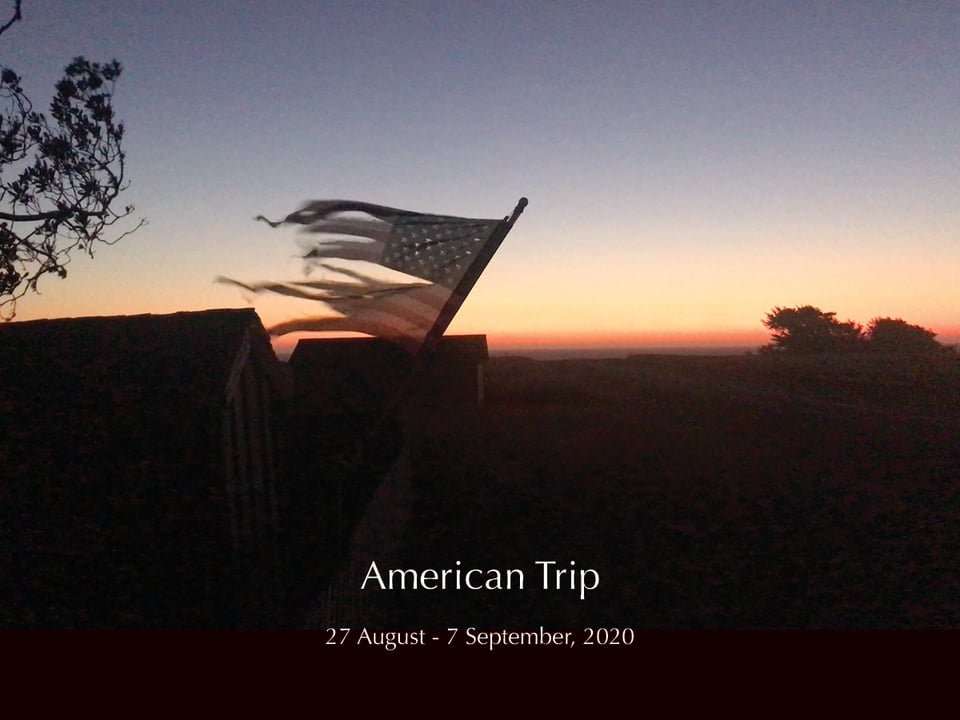 A slide with the image of a tattered American flag in front of a sunset and the text, "American Trip: 27 August - 7 Steptember, 2020"