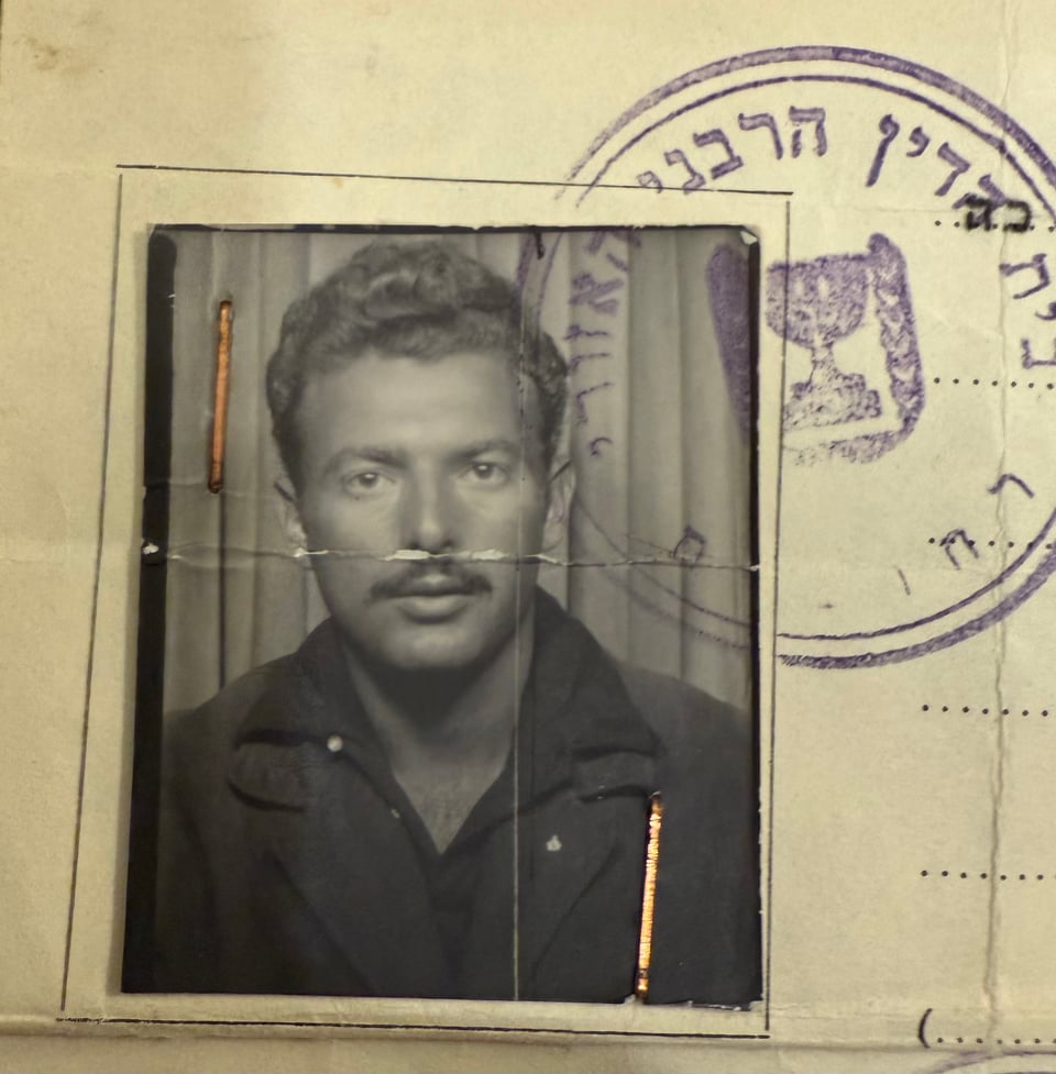 b/w photo of a white man in the 1960s, wearing a dark dress shirt with a wide collar, over a sportcoat. It's part of an official document, and there's a stamp with Hebrew lettering beside the image
