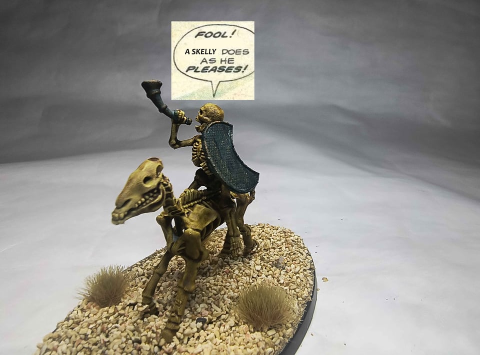 Photo of a skeleton riding a horse skeleton blowing into a bronze horn. There has been a text bubble put above the skeleton that says "Fool! A skelly does as he pleases!"