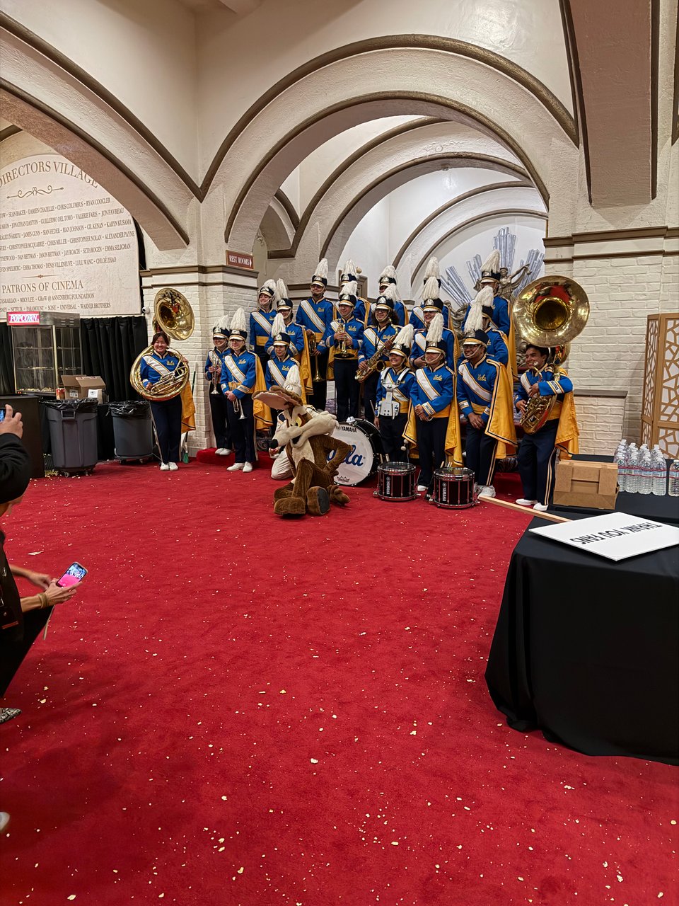 Popcorn all over the red carpet. Directors Village lobby. UCLA band posing with Wille E. Coyote mascot.