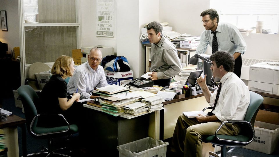 A scene from Spotlight where all the journalists discuss on a busy deskk.
