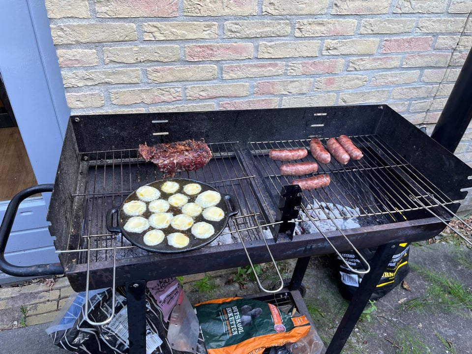 BBQ is in a back patio and has six sausages, a hunk of meat and a cast iron pan with dimples filled with melted provolone cheese.