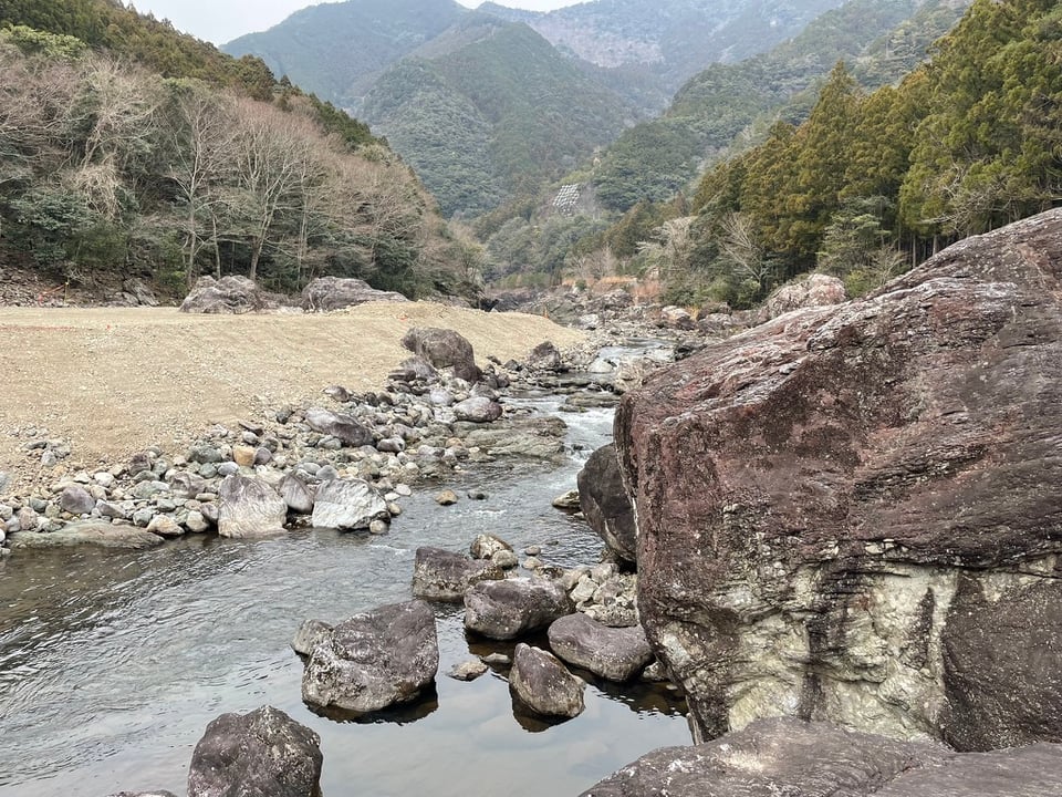 Miyagawa river, with the Amego boulder on the right. Chunky rocks are scattered along the river side.