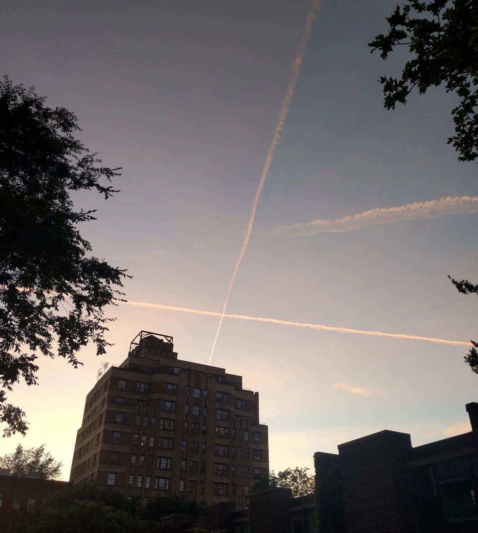 Photograph of the evening sky over Brooklyn Heights with two contrails forming a cross.
