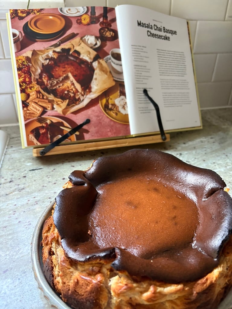 A properly browned basque cheesecake in the foreground of the recipe for the cheesecake.