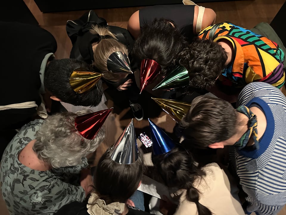 A group of people wearing birthday hats from above.