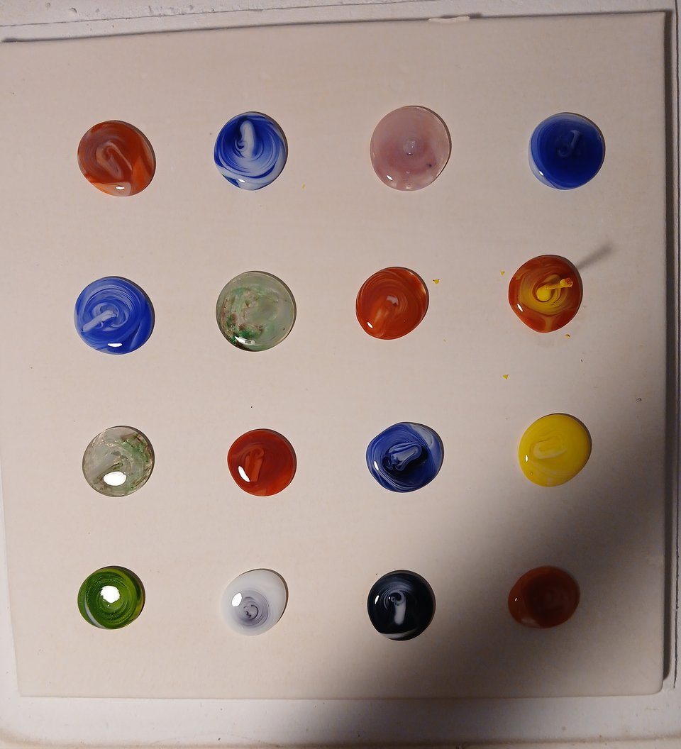 kiln shelf with 16 swirling cabochons, a couple of them have "tails" coming up from them that broke off from the pots, those will need to refire