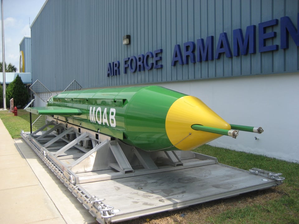 A large green missile with a yellow cap and antennae. The letters MOAB are on the side in white.