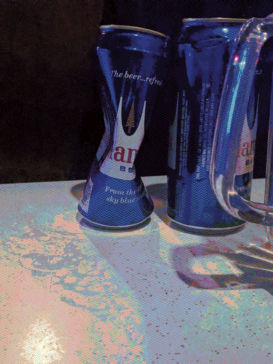 Two cans of Hamm's beer on a table. One is partially crushed.