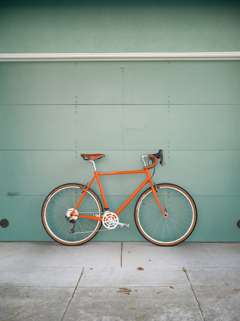 Bill's orange bike, leaning against a green garage door.