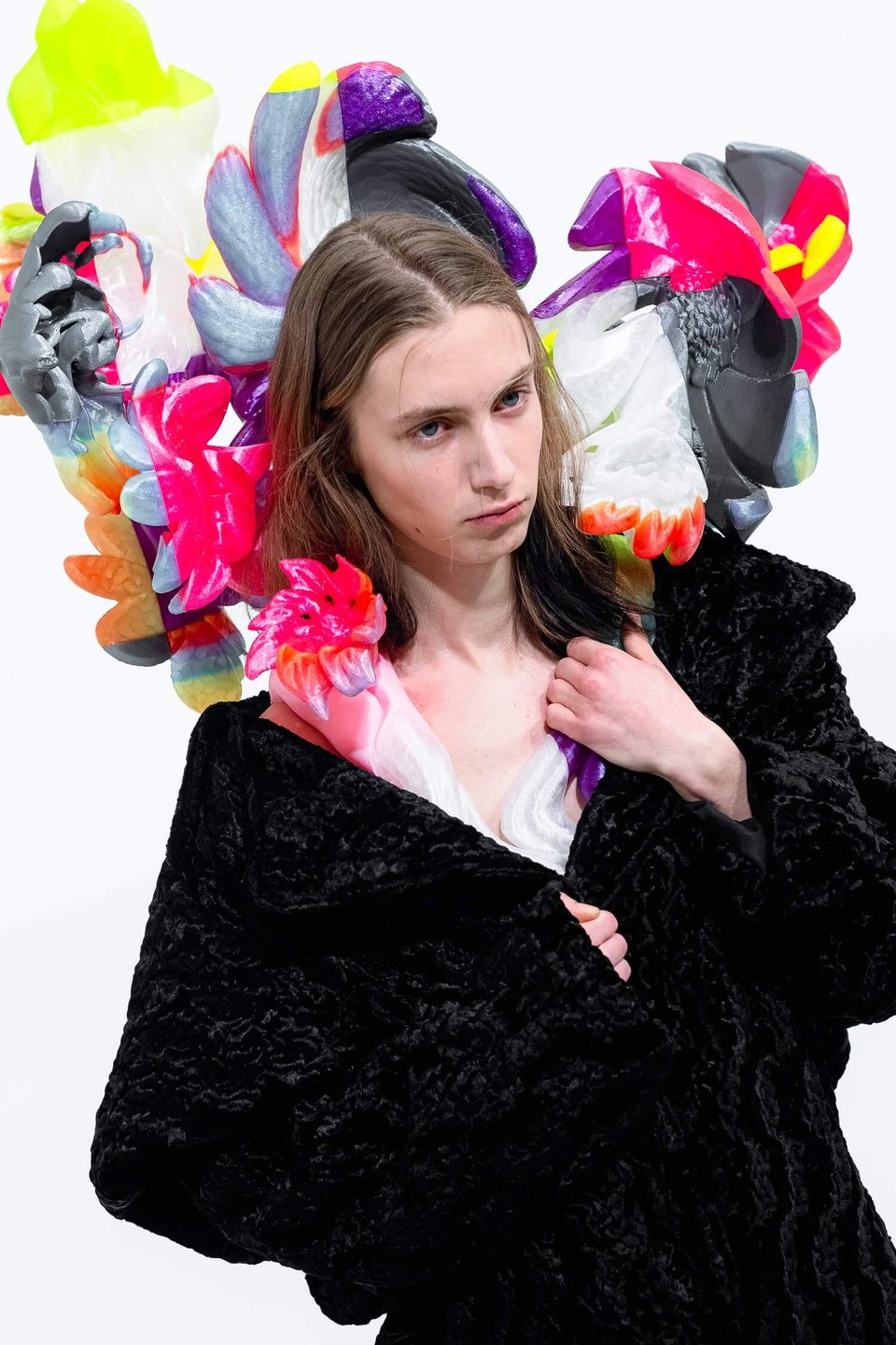 A person wearing an elaborate, shape-shifting neck sculpture