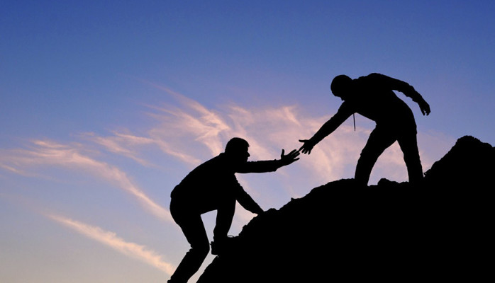 a photograph of someone helping another person up a hill