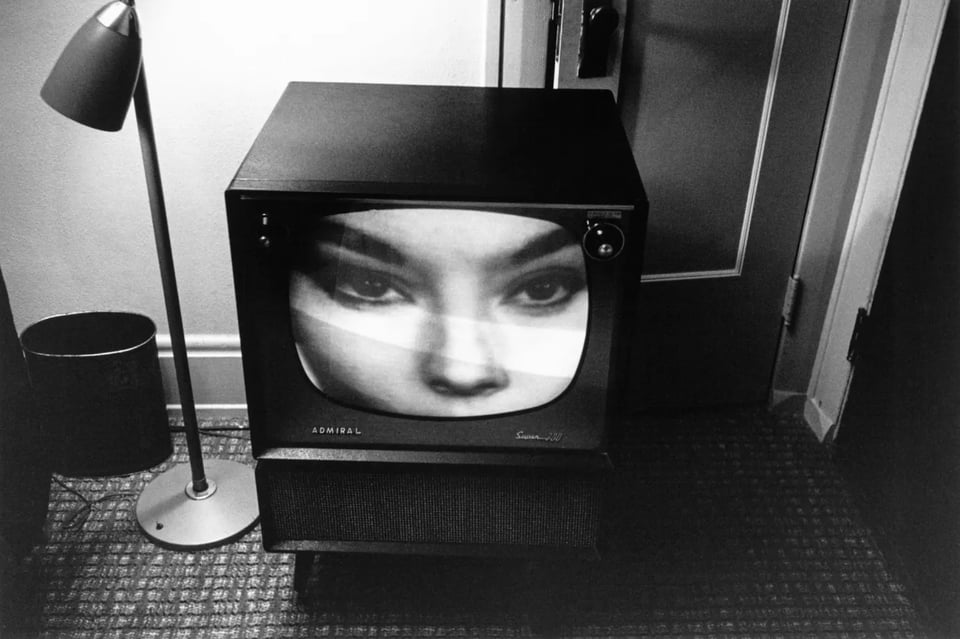 black and white photograph of a television screen with a close up image of a woman's eyes as she looks at something off camera right
