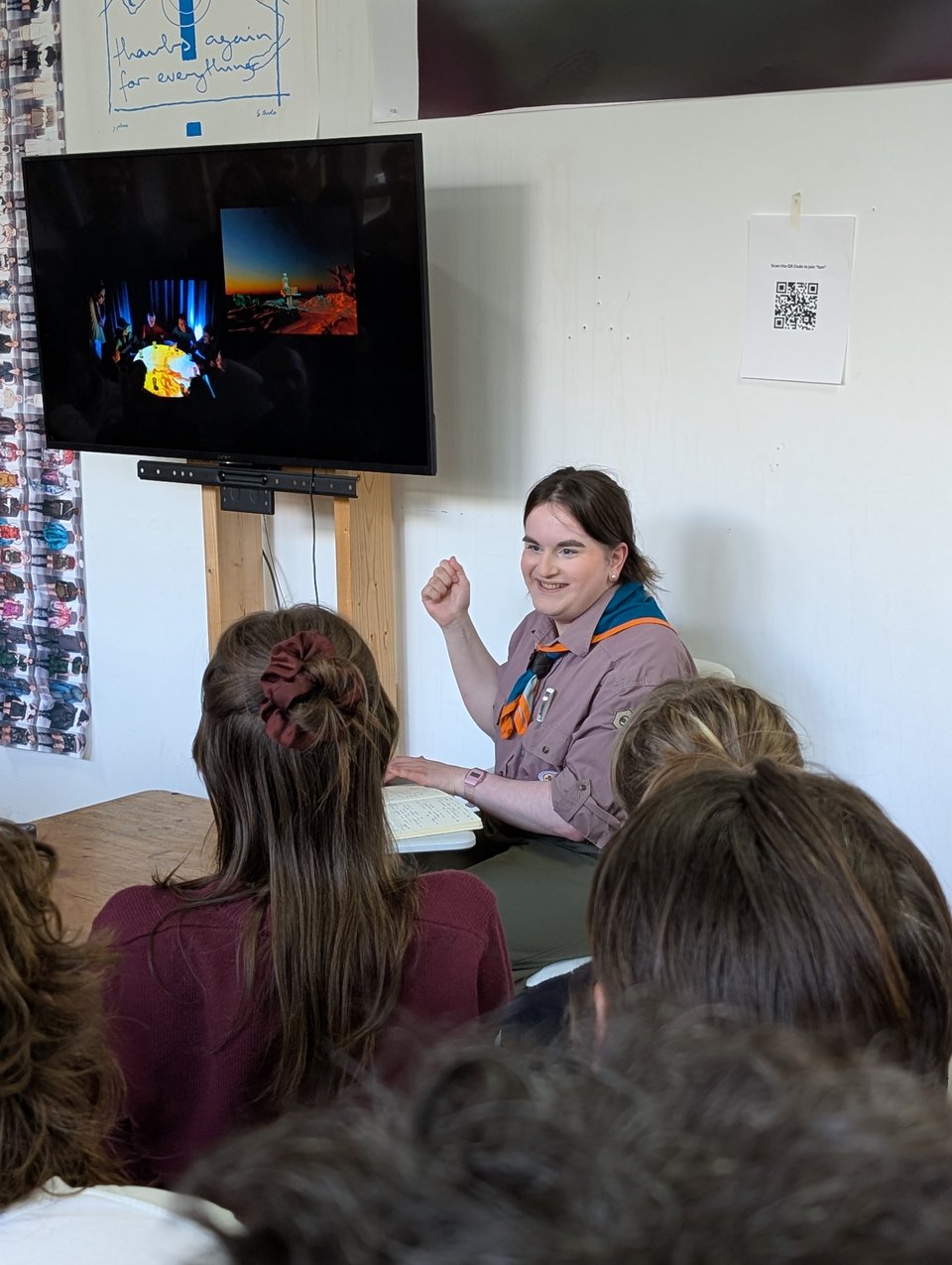 A presenter in a Scouts uniform gestures at the screen during her presentation.