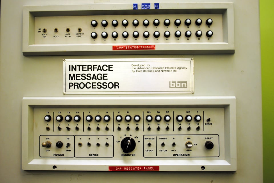 Two white analogue control panels with a combination of switches and dials in them. There is a label in the middle that says Interface Message Processor. Developed for the Advanced Research Projects Agency by Bolt Baranek and Newman Inc. There are two ed dymo printed labels attached; the first (under the first panel) says "imp status panel", the second "imp register panel".