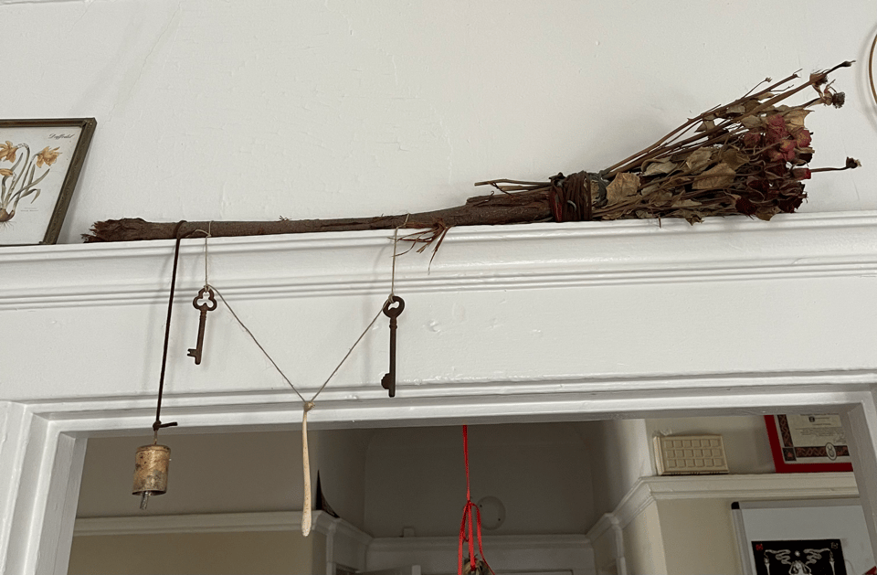 a homemade broom with rose bristles hangs above a doorframe.