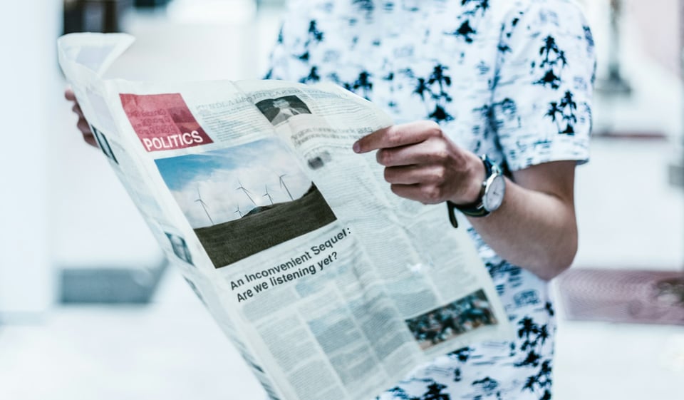 A person holding a newspaper open. Photo by Priscilla Du Preez 🇨🇦 on Unsplash