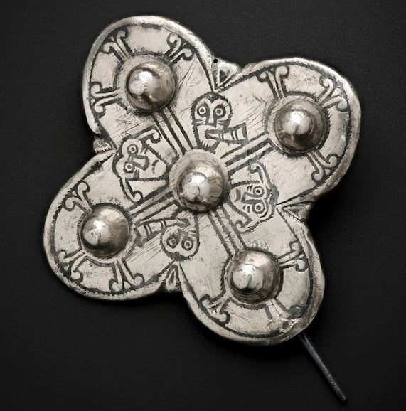 cross shaped brooch with figures as decoration