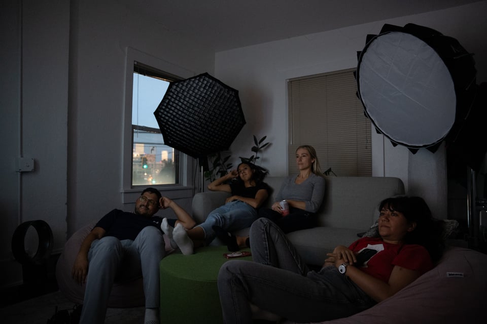 A group of people in a dark room watching a TV.