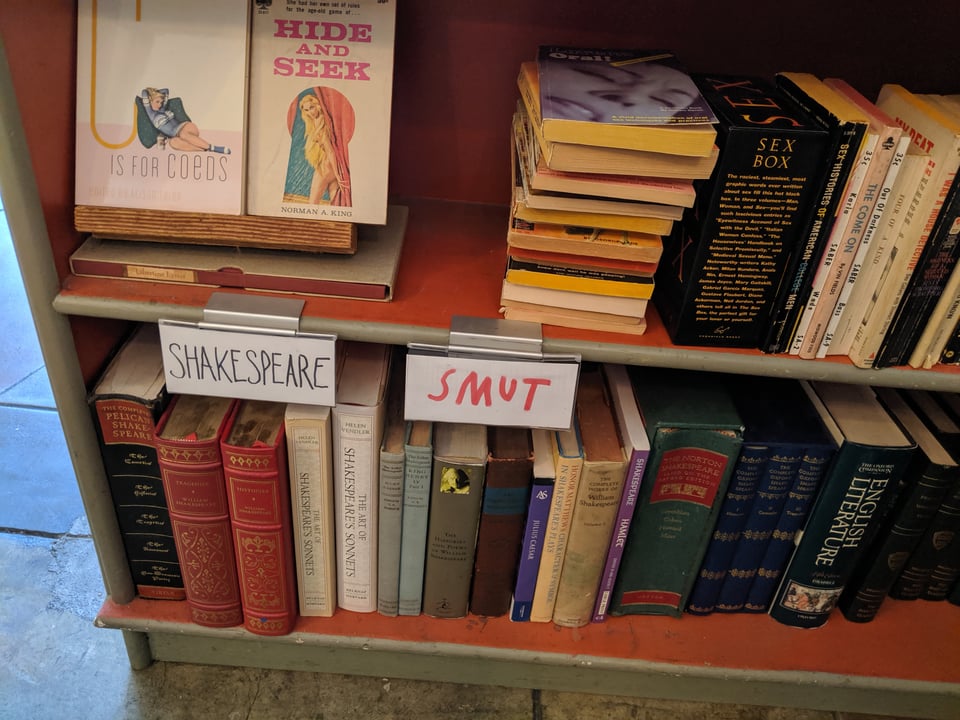 A bookstore shelf that is divided between Shakespeare and Smut. The upper shelf is a bunch of erotica and books about sex. The bottom shelf is, you guessed it, all Shakespeare.
