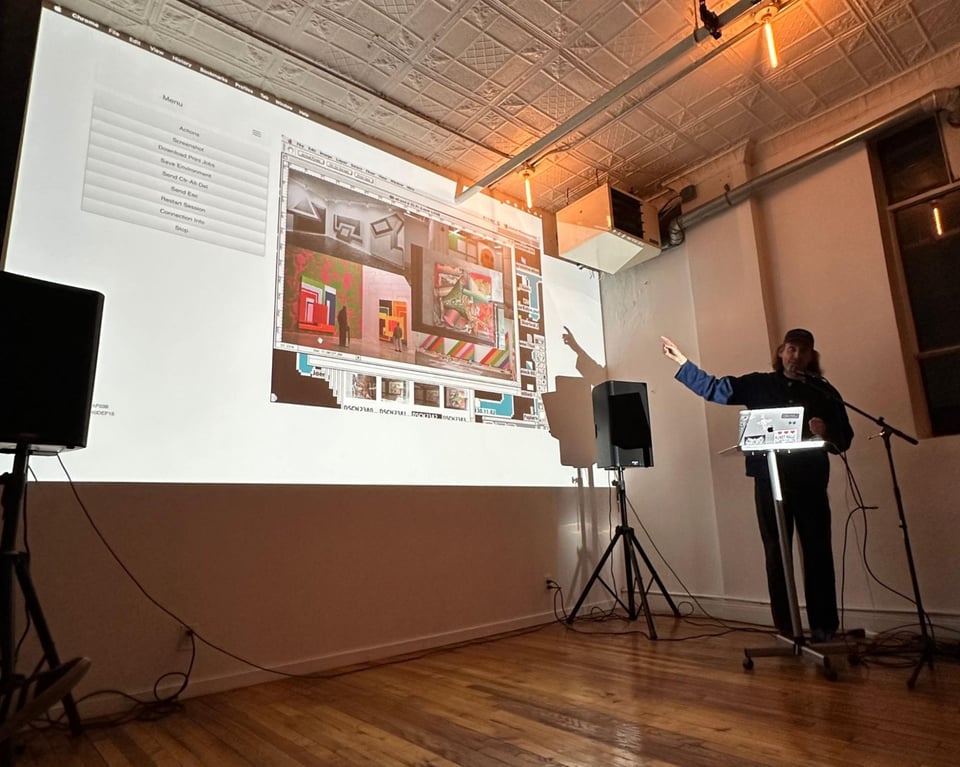Cory in front of a laptop and a microphone, pointing to a projection of a game screen.