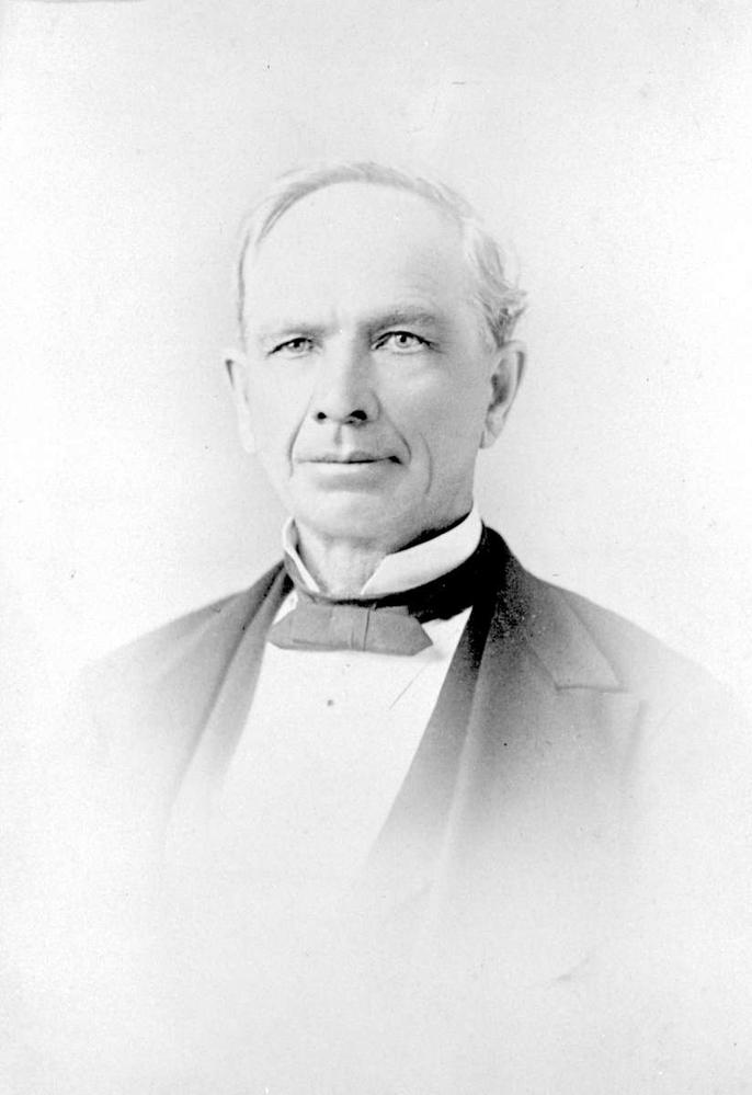 Black and white portrait of a white man with short hair wearing a bowtie and suit jacket