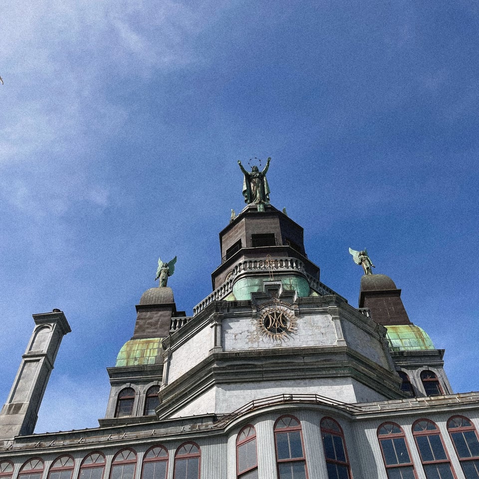 a figure atop an old church reaches to a beautiful blue sky with a halo of stars