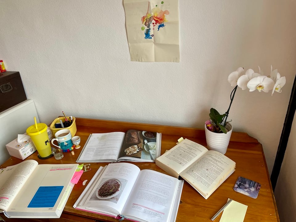 Four cookbooks open on a desk