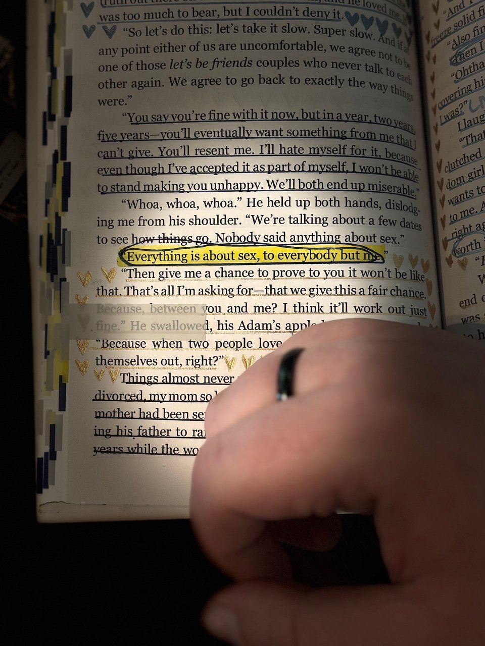 Ace of Hearts by Lucy Mason open to a page that's annotated. The line "everything is about sex, to everybody but me" is highlighted. A white person's hand rests on the page, with a black asexual pride ring on their middle finger.