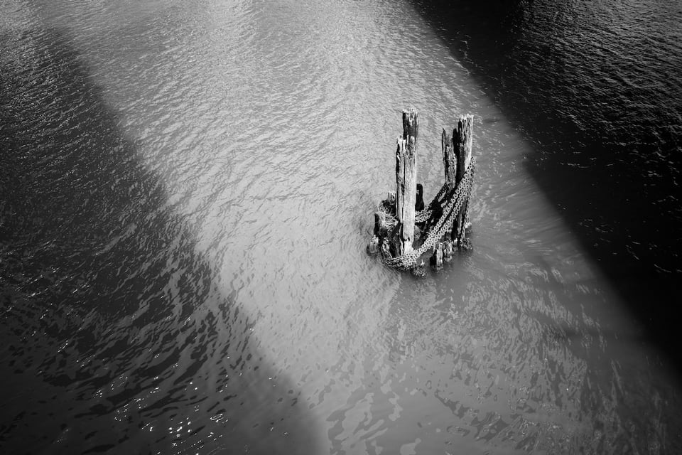 A pier with chains around it sit in a shaft of light in the Chicago river.