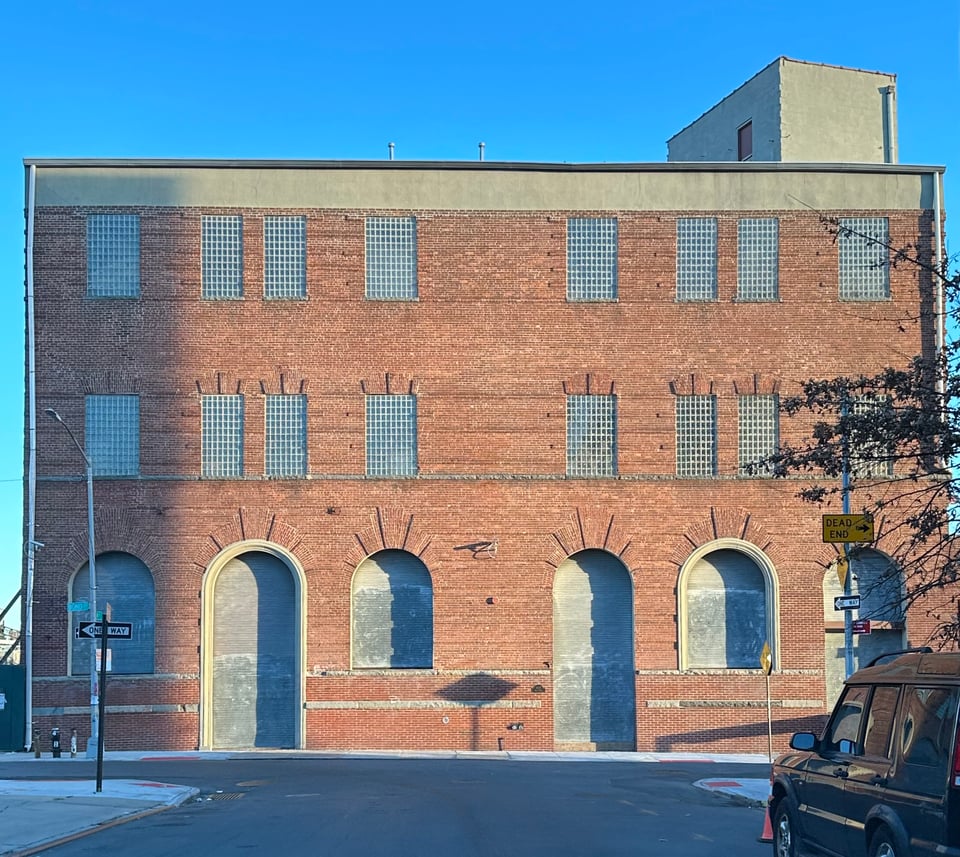 photo of 3 story brick building in golden-hour light, with a blue sky behind it