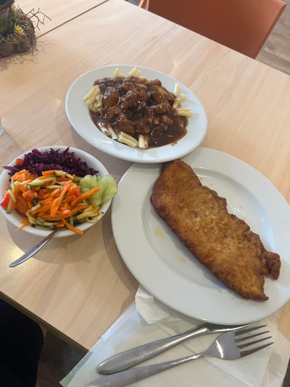 3 plates: a schnitzel, pasta with brown sauce on top, and a bowl of pickled salads.