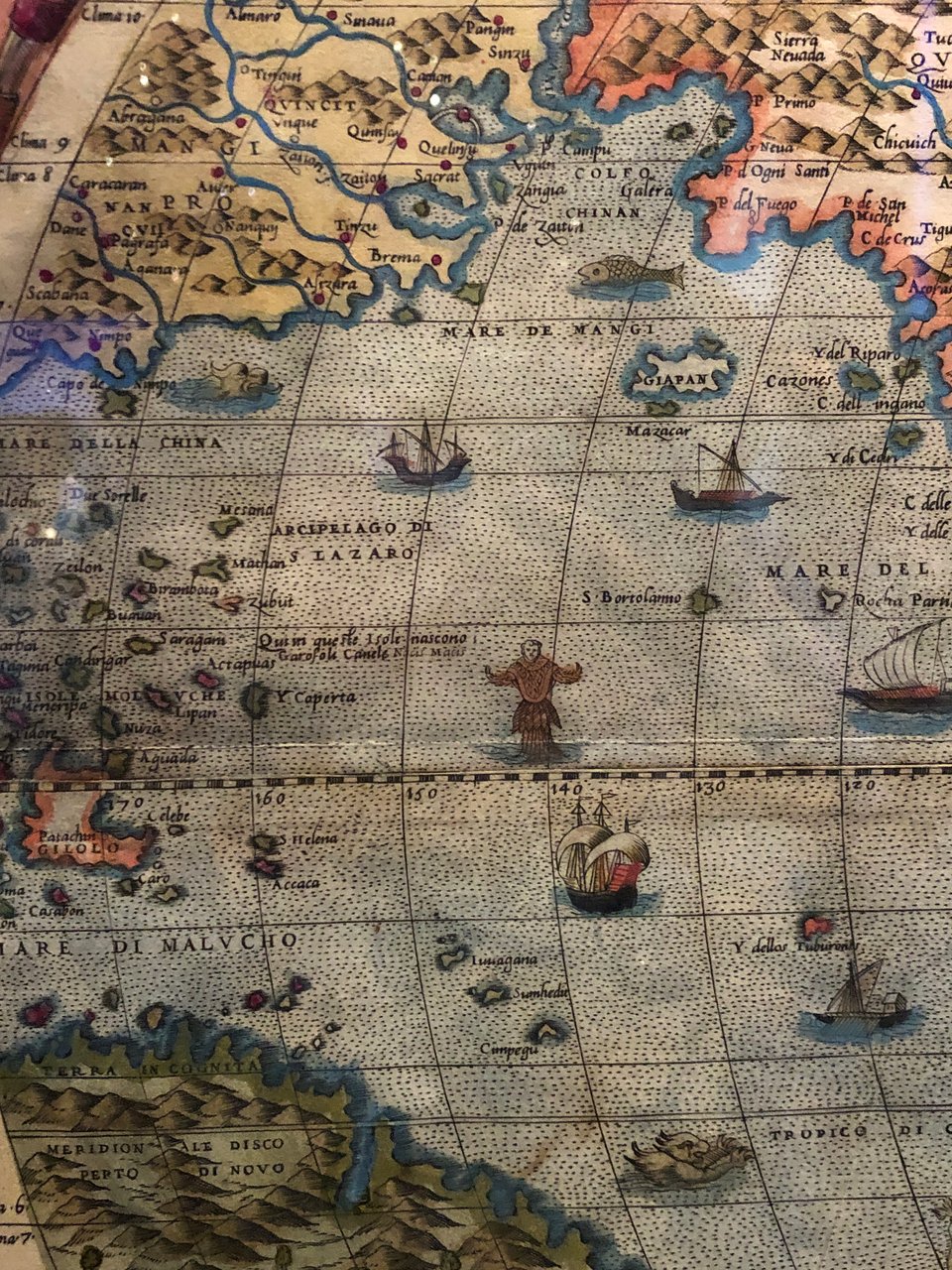 Map detail of a rather small Pacific Ocean (swathes of the Americas and Asia are also visible when in fact the ocean takes up pretty much a whole hemisphere). Ther are a few ships and islands in the sea. In the centre of the detail is a fishy creature with a human head.