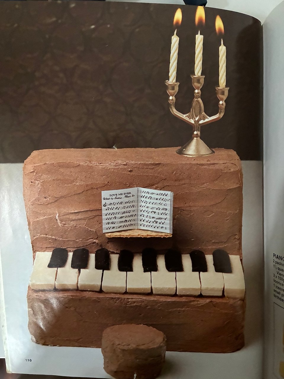 cake shaped to look like a piano with keys, footstool, and music sheets