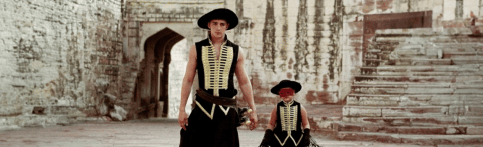 A screenshot from The fall. Lee Pace, dressed as a bandit, stands in an old city with a little girl in matching garb.