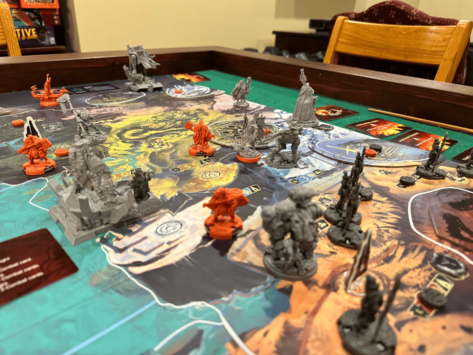 Orange and gray plastic minis spread out over a board game map.