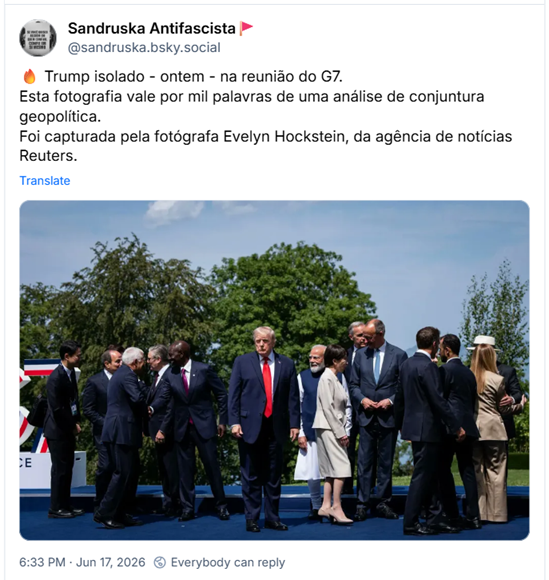 Post de Sandruska Antifascista🚩 (‪@sandruska.bsky.social‬): 🔥 Trump isolado - ontem - na reunião do G7. Esta fotografia vale por mil palavras de uma análise de conjuntura geopolítica.
Foi capturada pela fotógrafa Evelyn Hockstein, da agência de notícias Reuters. (fotografia de um encontro do G7 ao ar livre, com participantes vestidos em trajes formais sobre um palco azul. No centro da composição, Trump usando terno azul-marinho, camisa branca e gravata vermelha está sozinho e olhando pra câmera, com expressão séria e braços ao lado do corpo. Ao redor dele, vários outros participantes estão reunidos em pequenos grupos, conversando, cumprimentando-se ou voltados uns para os outros, o que cria um contraste visual entre a figura central isolada e as demais interagindo entre si. À esquerda, dois homens apertam as mãos enquanto outros observam ou conversam próximos. À direita, há grupos adicionais de homens de terno e uma mulher de cabelos longos usando um conjunto bege e chapéu branco, vista de costas. Ao fundo, árvores verdes e um céu azul com poucas nuvens sugerem um dia ensolarado em um ambiente externo. Parte de uma estrutura decorativa com faixas vermelhas, brancas e azuis aparece na lateral esquerda da imagem)