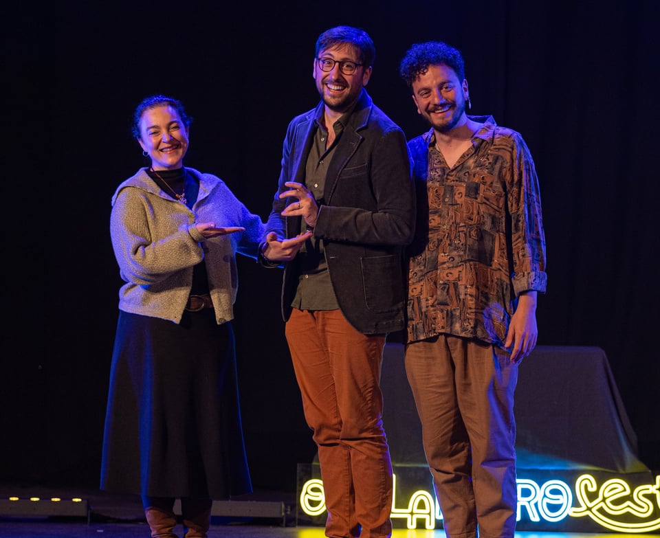 Gael receiving an invisible award surrounded by two jury members