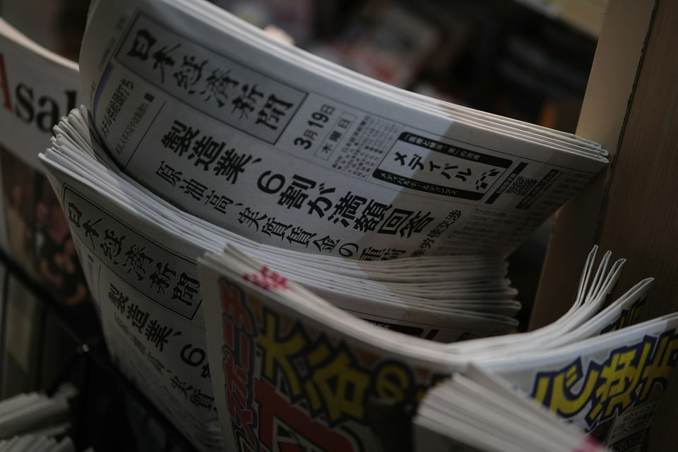 A black-and-white photo of newspapers laid out on a table. Photo by Haberdoedas on Unsplash