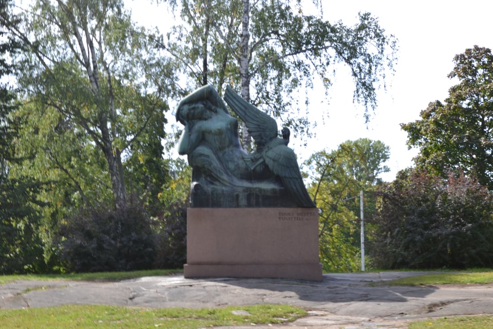 A statue of a woman on a chaise longe, accompanied by a large bird - a goose or swan.