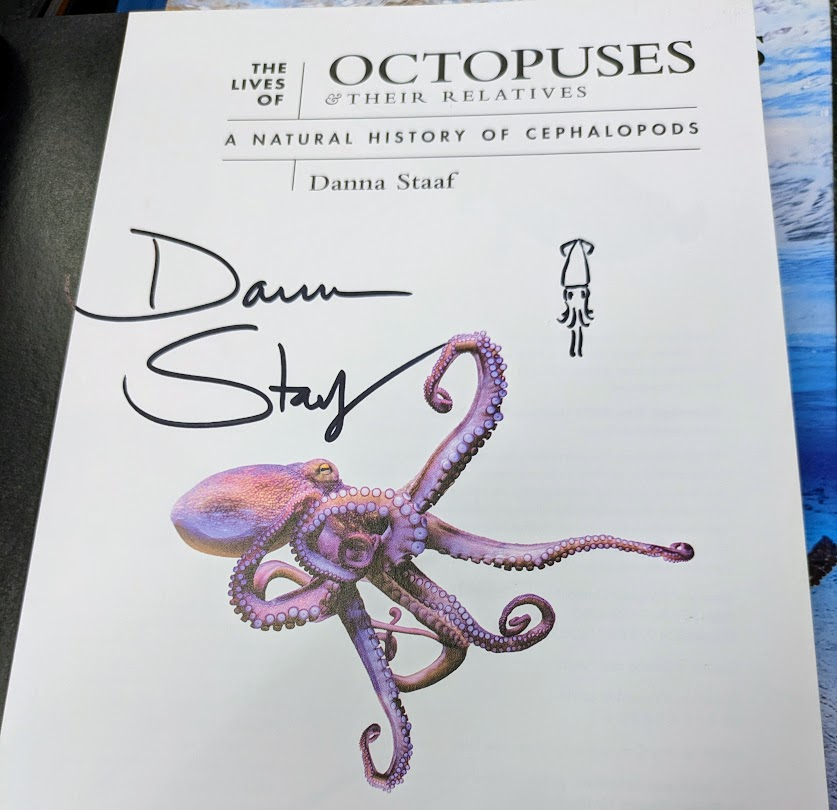 Photo of the title page of The Lives of Octopuses, with my signature and a cute little squid doodle.